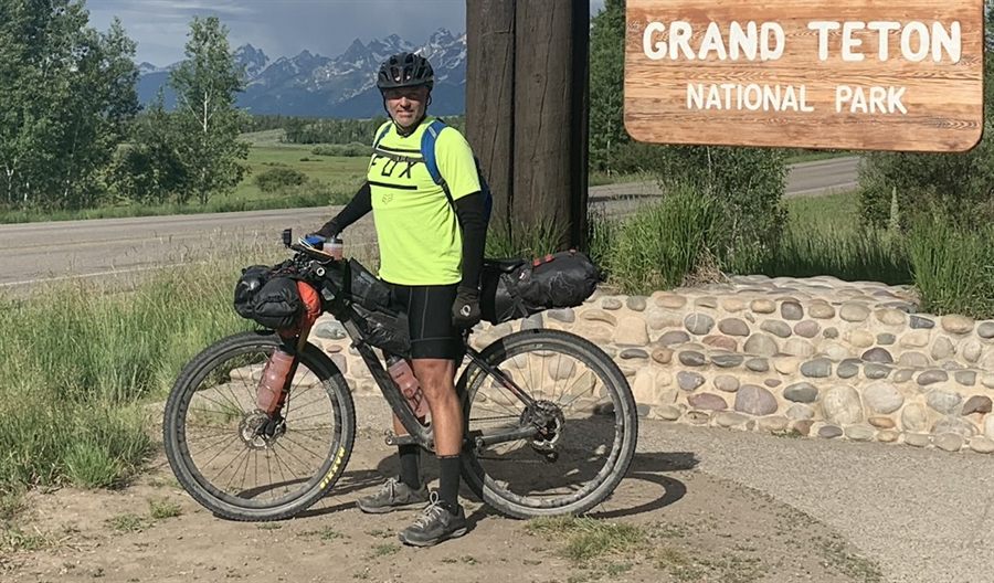 Jeff with a loaded bikepacking rig at the Grand Teton National Park sign